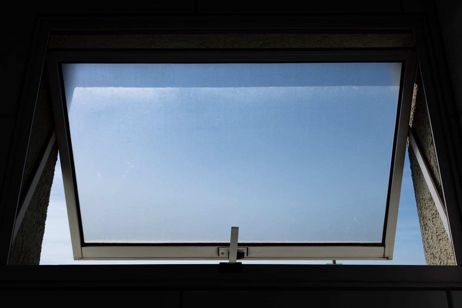 A window opened onto a bright day, airing out a room